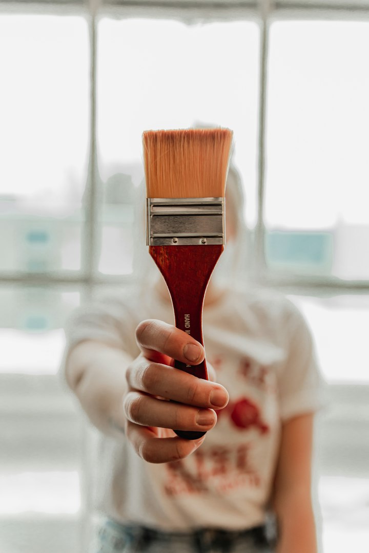 Japanese female art teacher providing guidance to her male student, who is focused on painting on canvas at home. Using an easel and a vibrant color palette, they engage in creative learning